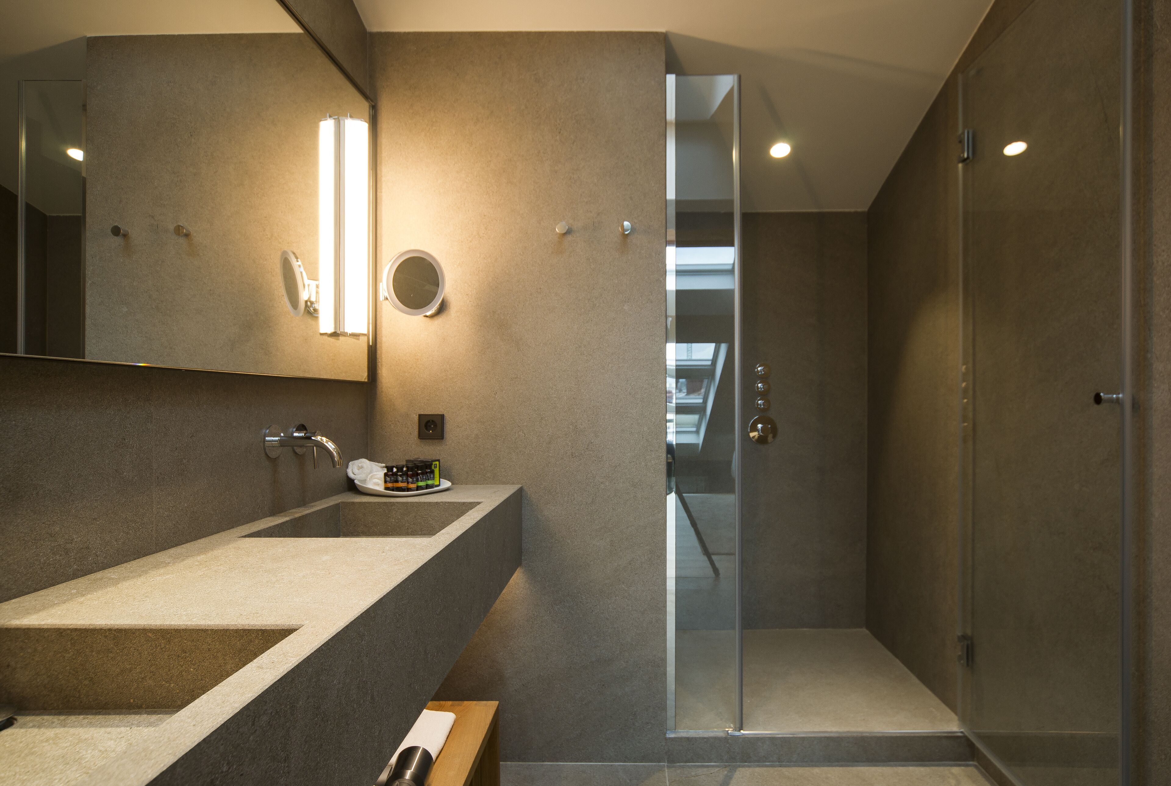Un baño moderno con un espejo grande, un lavamanos y una zona de ducha.