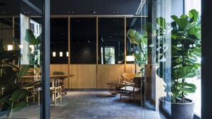 A modern interior with glass walls, wooden furniture, and potted plants. - Hotel Arbaso (San Sebastián)