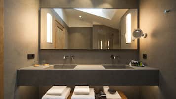 A modern bathroom with a large mirror, dual sinks, and a wooden vanity with towels.