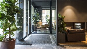 A modern hotel lobby with large windows, a reception desk, and a seating area with a sofa and coffee table. - Hotel Arbaso (San Sebastián)