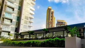 A modern building with multiple floors, large windows, and a rooftop garden with various plants. - Legoland D'Pristine Apartment by TGP (Iskandar Puteri)