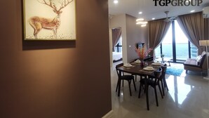 A modern hotel room with a dining area, a large window with curtains, and a TGPGROUP logo on the ceiling. - Legoland D'Pristine Apartment by TGP (Iskandar Puteri)