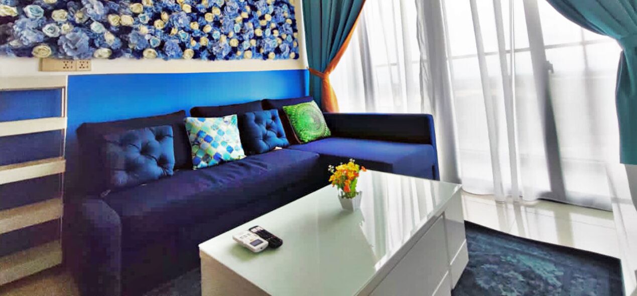 A room with a dark blue sofa, a white coffee table, and a wall with a blue and white floral pattern.
