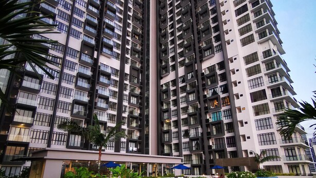 A high-rise residential building with multiple balconies and a swimming pool area with a tiled deck and lounge chairs. - Legoland D'Pristine Apartment by TGP (Iskandar Puteri)