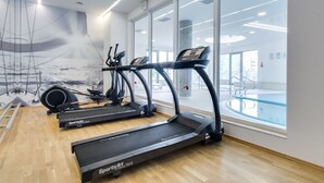 Ein modernes Fitnessstudio mit drei Laufbändern, einem Rudergerät und einem Ergometer.