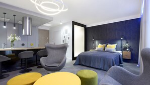 Ein modernes Hotelzimmer mit einem großen Bett, einem Schreibtisch und einer Sitzecke mit Poufs.