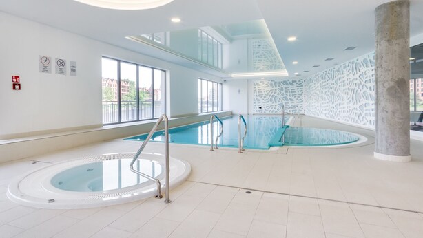 Ein Innenpool mit Whirlpool, klaren Glasgeländern und einem modernen Deckenbau.