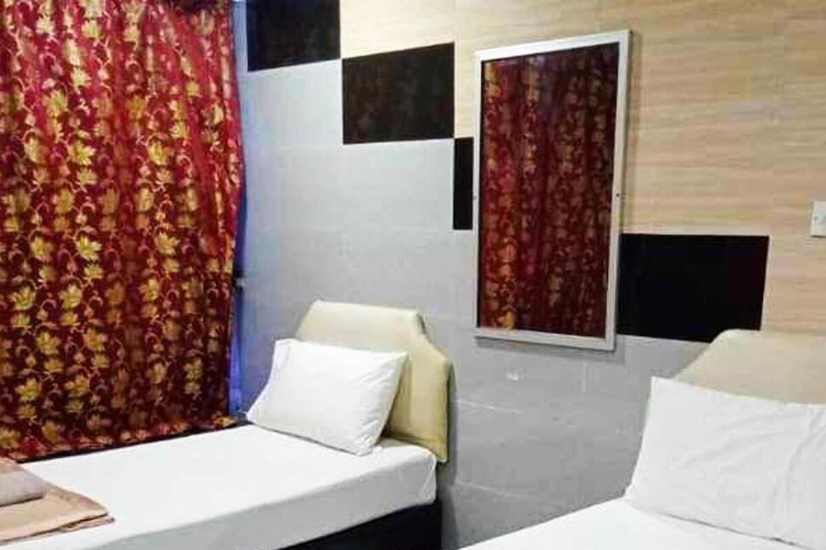 A hotel room with two beds, each with white linens and a brown decorative item on the bed.