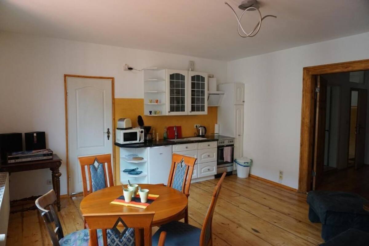 A compact kitchen with white cabinets, a microwave, and a stove. There is a dining table with chairs and a small TV on a table.