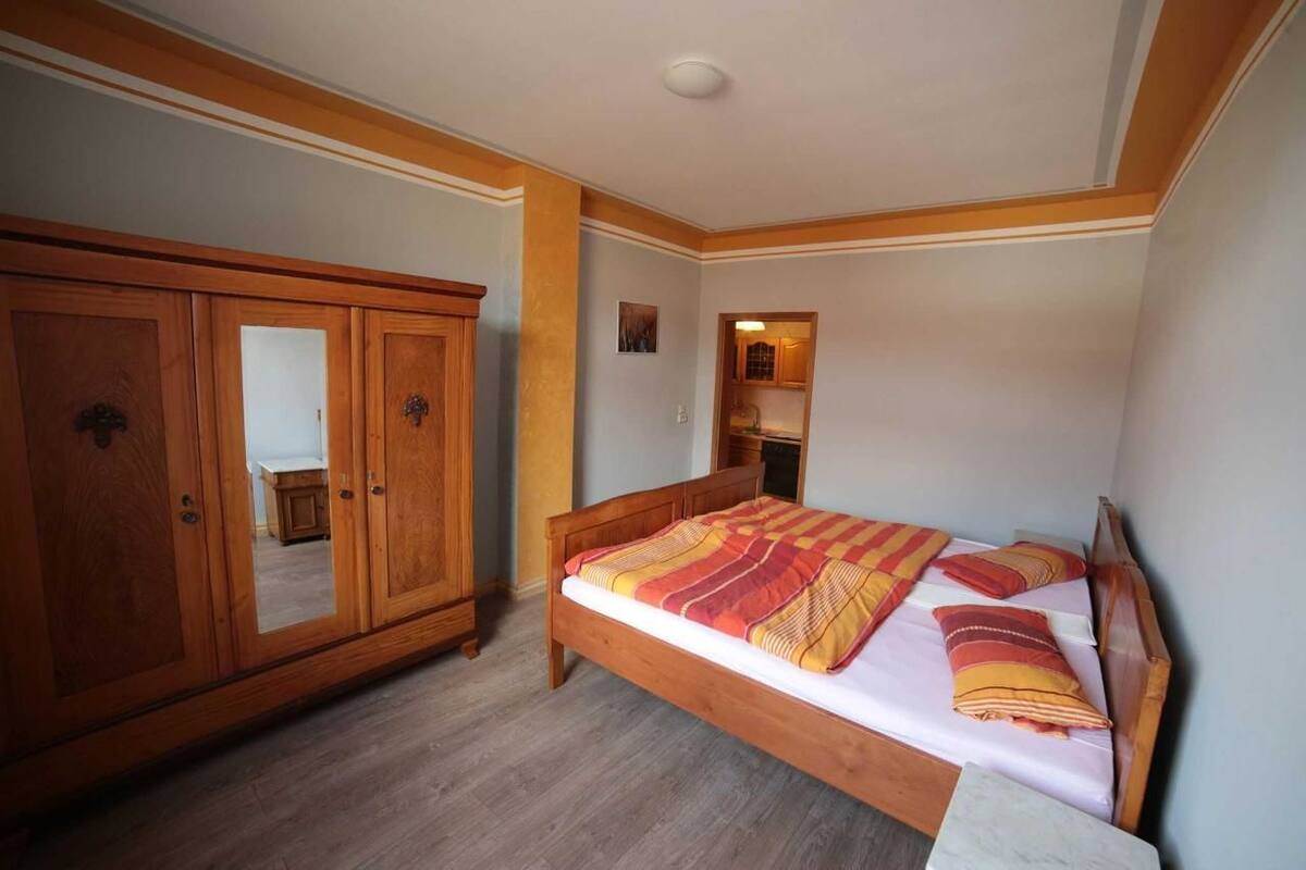 A bedroom with a wooden bed, a wardrobe, and a mirror.