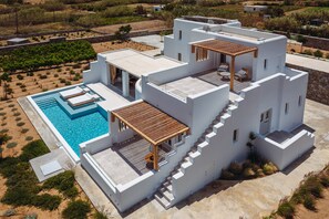 A modern, multi-level white building with a rooftop pool and outdoor seating areas.