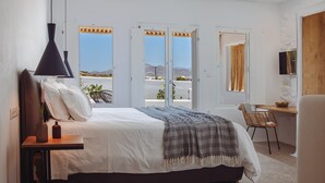 Ein Schlafzimmer mit Bett, Nachttisch, Lampe und Blick ins Freie.