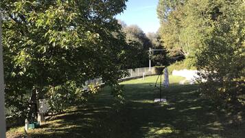 Un parc avec une pelouse, des arbres, une clôture en métal et un trépied sur lequel est posé un tissu.
