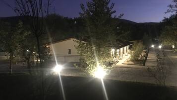 En bygning med en lysegrå facade, tydelig indgang og en belagt indkørsel til indgangen.