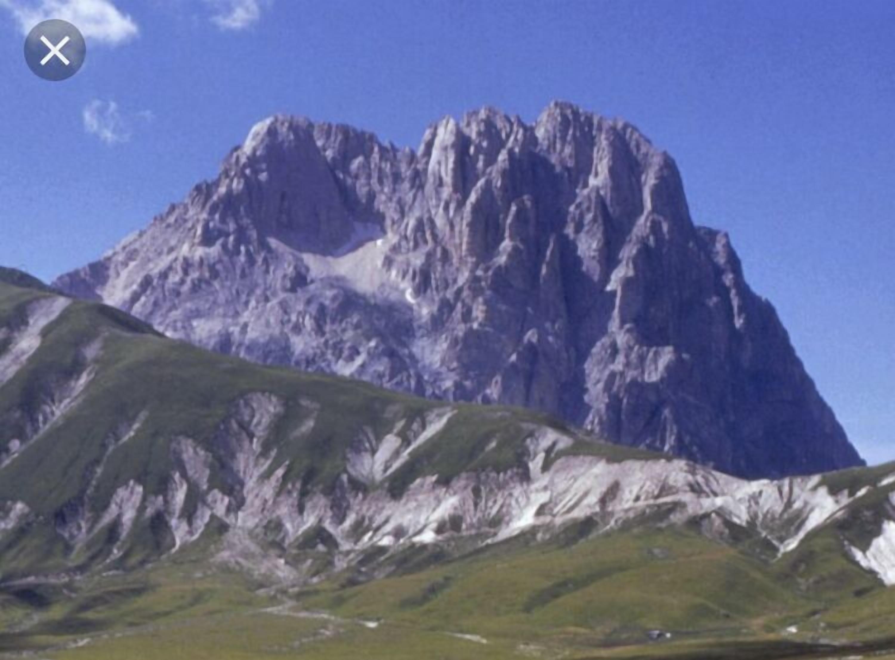 A mountain with a prominent peak and surrounding green slopes.