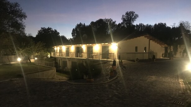 A building with a courtyard, outdoor seating, and a paved area. - Oasi del Vetoio (L'Aquila)