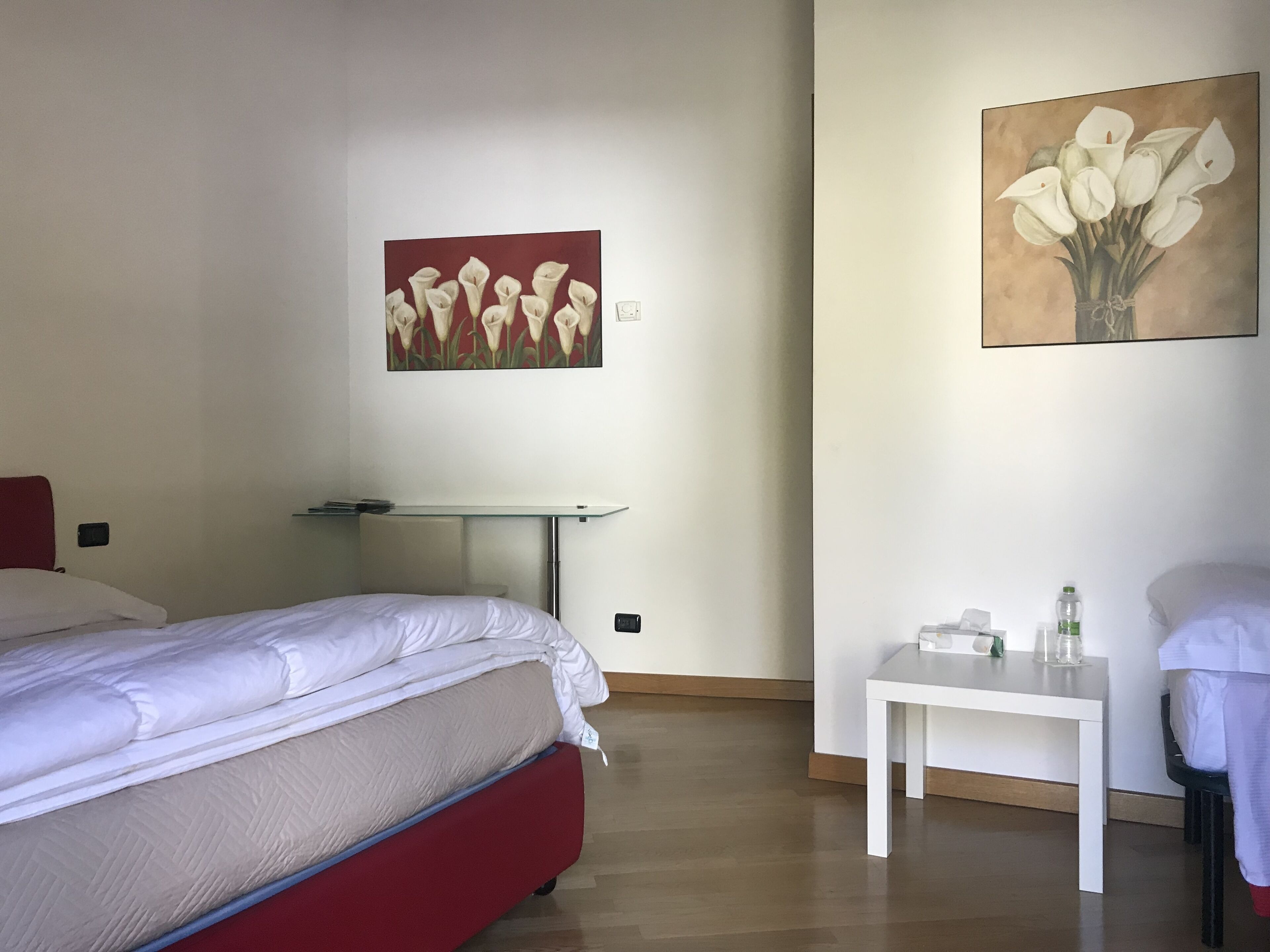 Habitación de hotel con dos camas, una mesita y dos cuadros en las paredes.