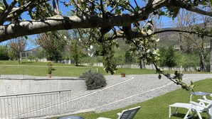 A patio area with outdoor seating, a paved walkway, and a view of a landscaped garden. - Oasi del Vetoio (L'Aquila)