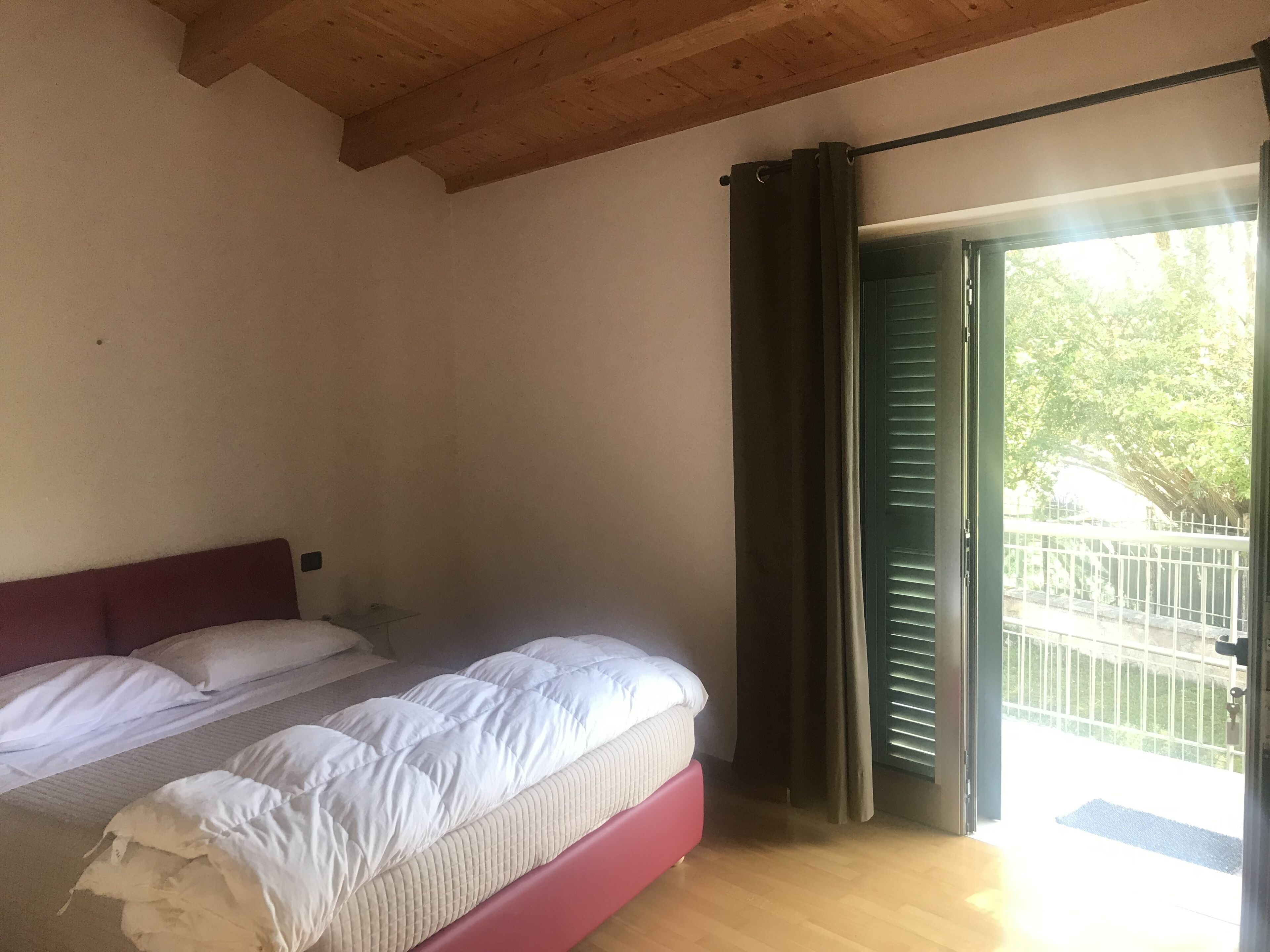 Un dormitorio con cama, techo de madera y puerta que da a un espacio exterior.