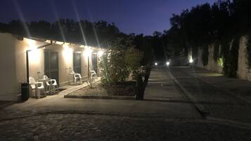 A courtyard with a seating area, a small garden, and a building with lights.