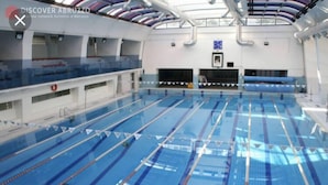 An indoor swimming pool with multiple lanes, a diving board, and a lifeguard chair. - Oasi del Vetoio (L'Aquila)