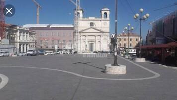A public square with a central monument, surrounding buildings, and a clear sky.