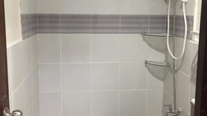 Un bany petit amb rajoles, dutxa, vàter i una barra per a tovalloles.