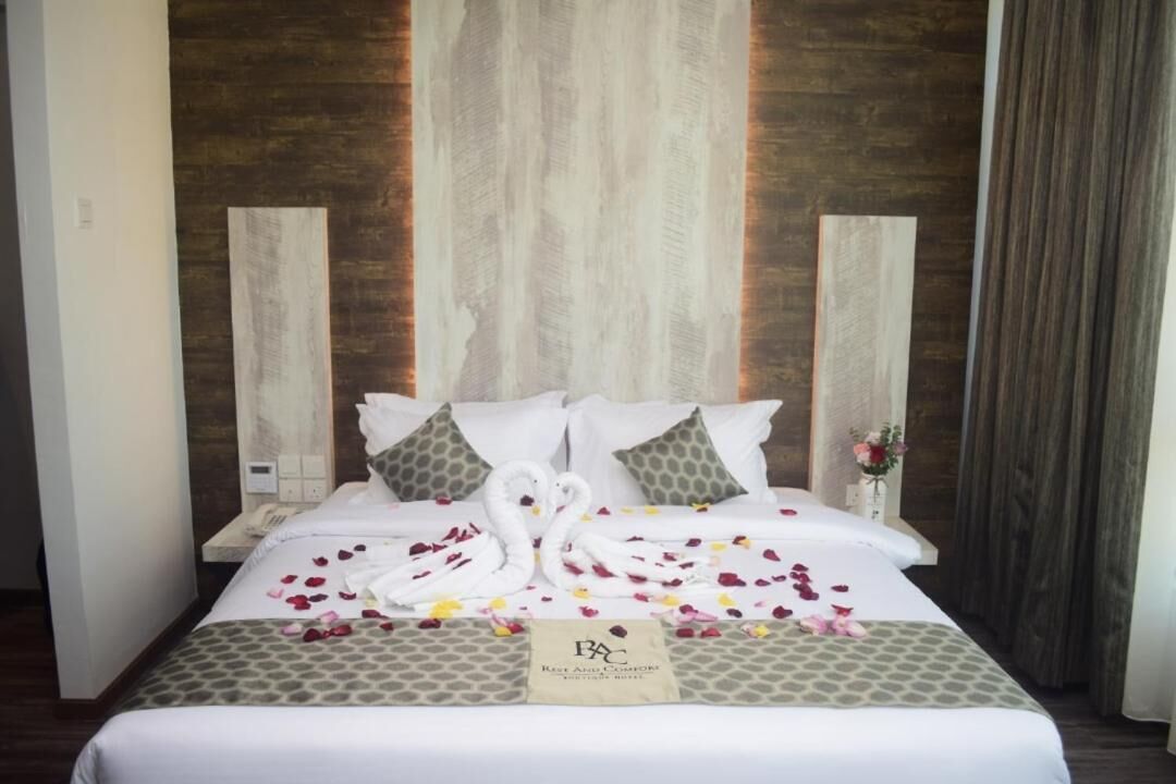 Una habitación de hotel con cama, almohadas, un cartel y una pared con paneles de madera verticales.