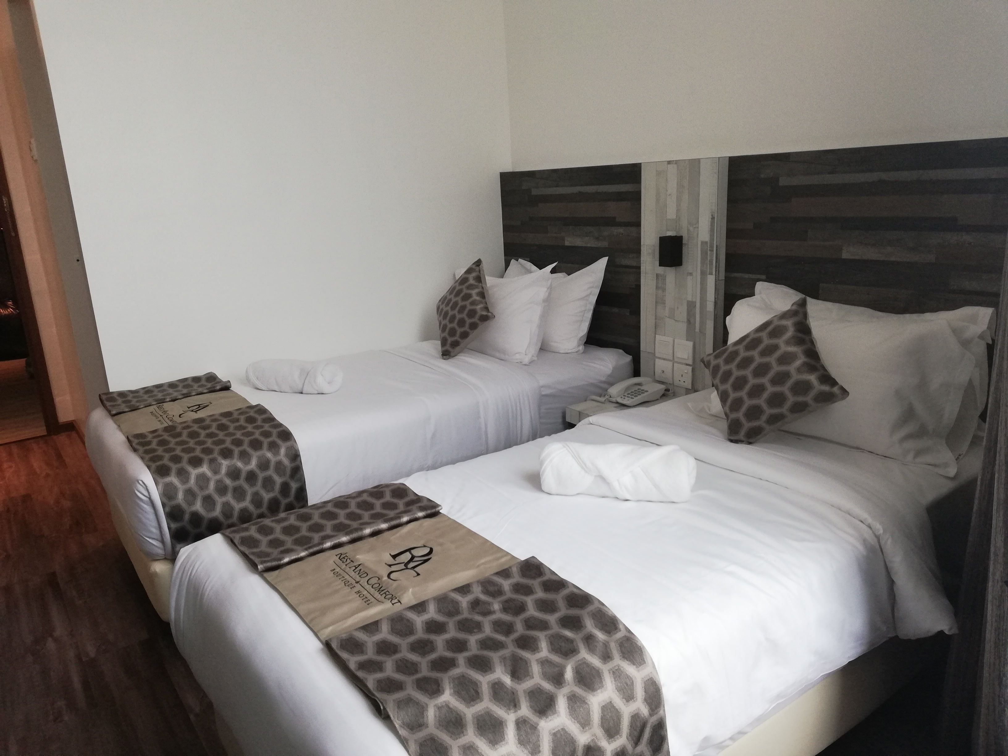 Habitación de hotel con dos camas, cada una con una colcha estampada y almohadas a juego. Hay un teléfono en la mesita de noche.