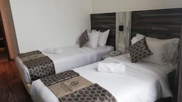 Habitación de hotel con dos camas, cada una con una colcha estampada y almohadas a juego. Hay un teléfono en la mesita de noche.