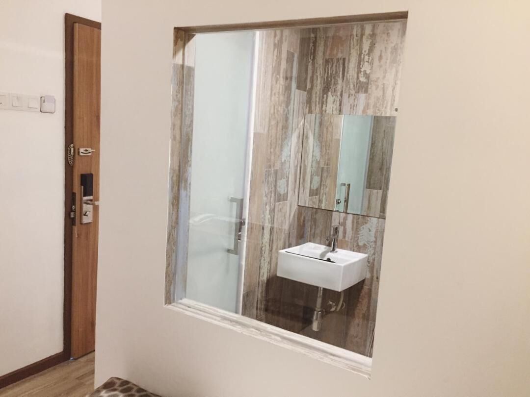 Un baño con cabina de ducha de vidrio, un lavabo blanco y una pared con textura de madera.