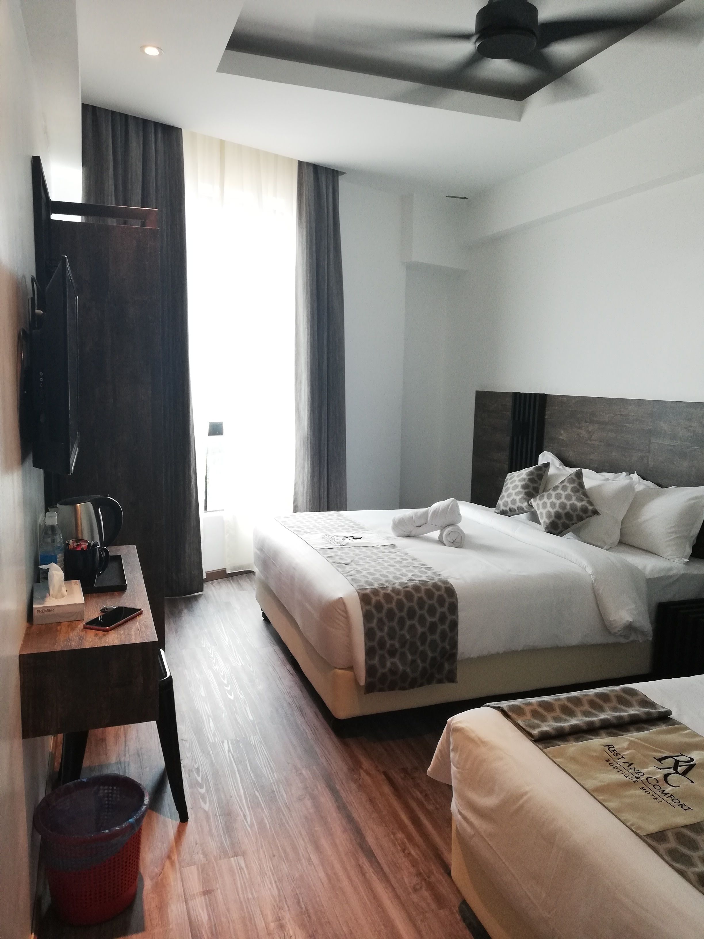 Een hotelkamer met een bed, nachtkastje en bureau met stoel.
