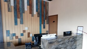A reception desk with a marble top, a wooden wall with geometric patterns, and a 'RECEPTION' sign. - Rest and Comfort Boutique Hotel (Kuala Terengganu)