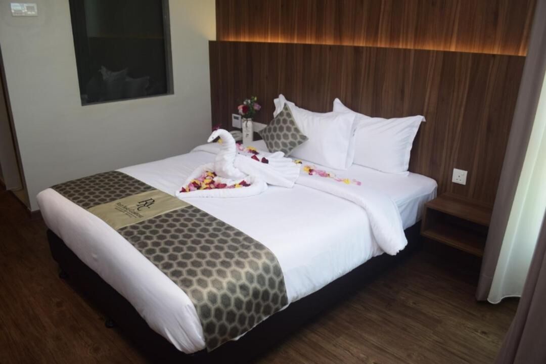 Una habitación de hotel con una cama bien hecha, cabecera de madera y ventana con vistas.