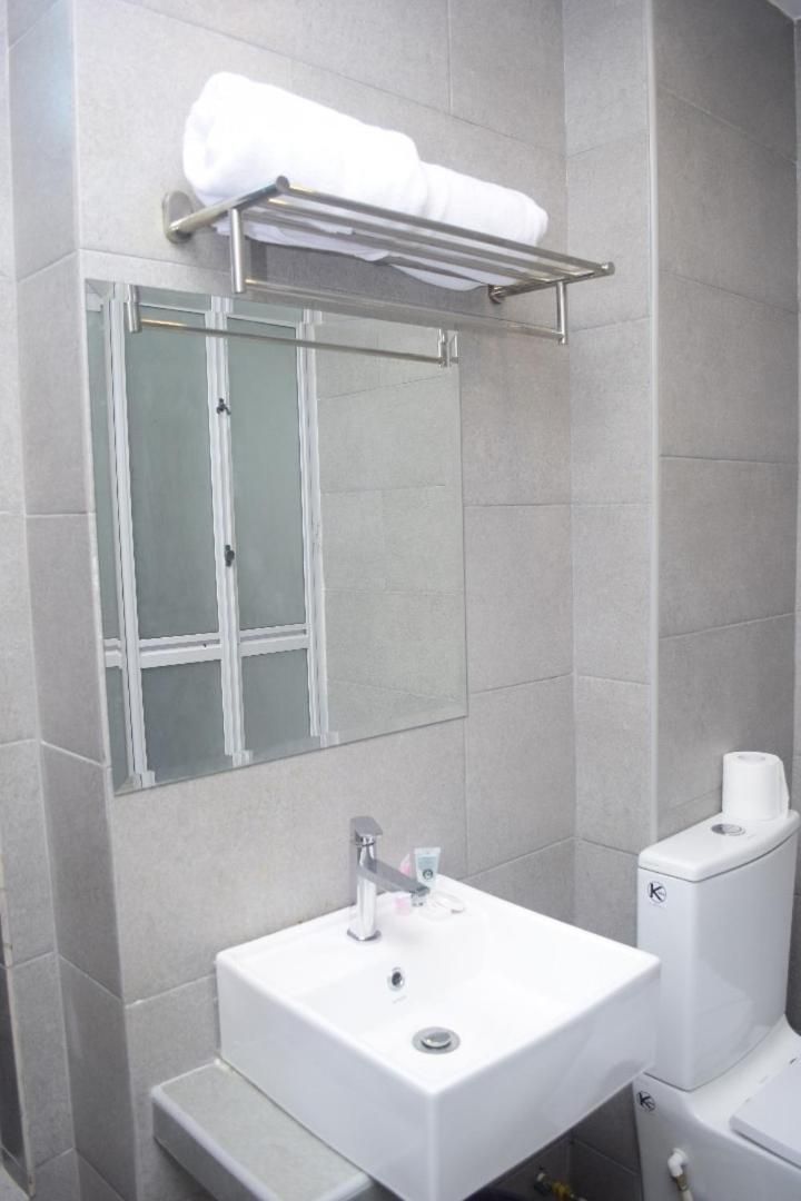 Ein Badezimmer mit einem weißen Waschbecken, einem Handtuchhalter, einer Duschkabine aus Glas und einer Toilette.