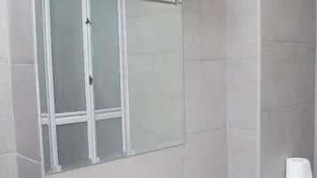 Ein Badezimmer mit einem weißen Waschbecken, einem Handtuchhalter, einer Duschkabine aus Glas und einer Toilette.