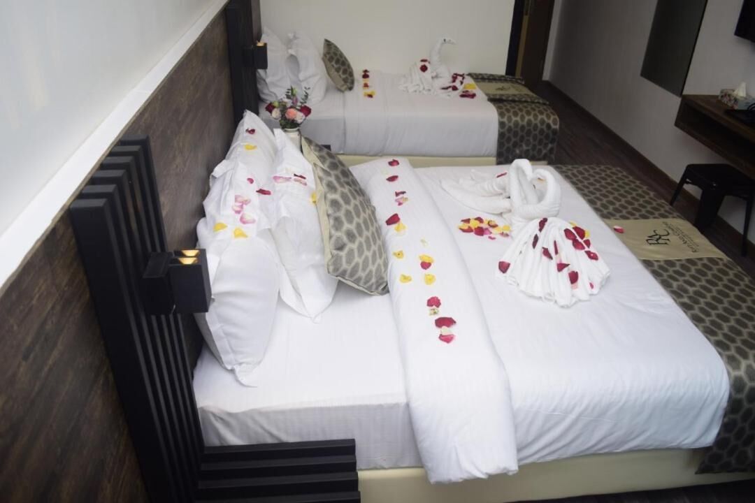 Habitación de hotel con dos camas, cada una con ropa blanca y almohadas decorativas.