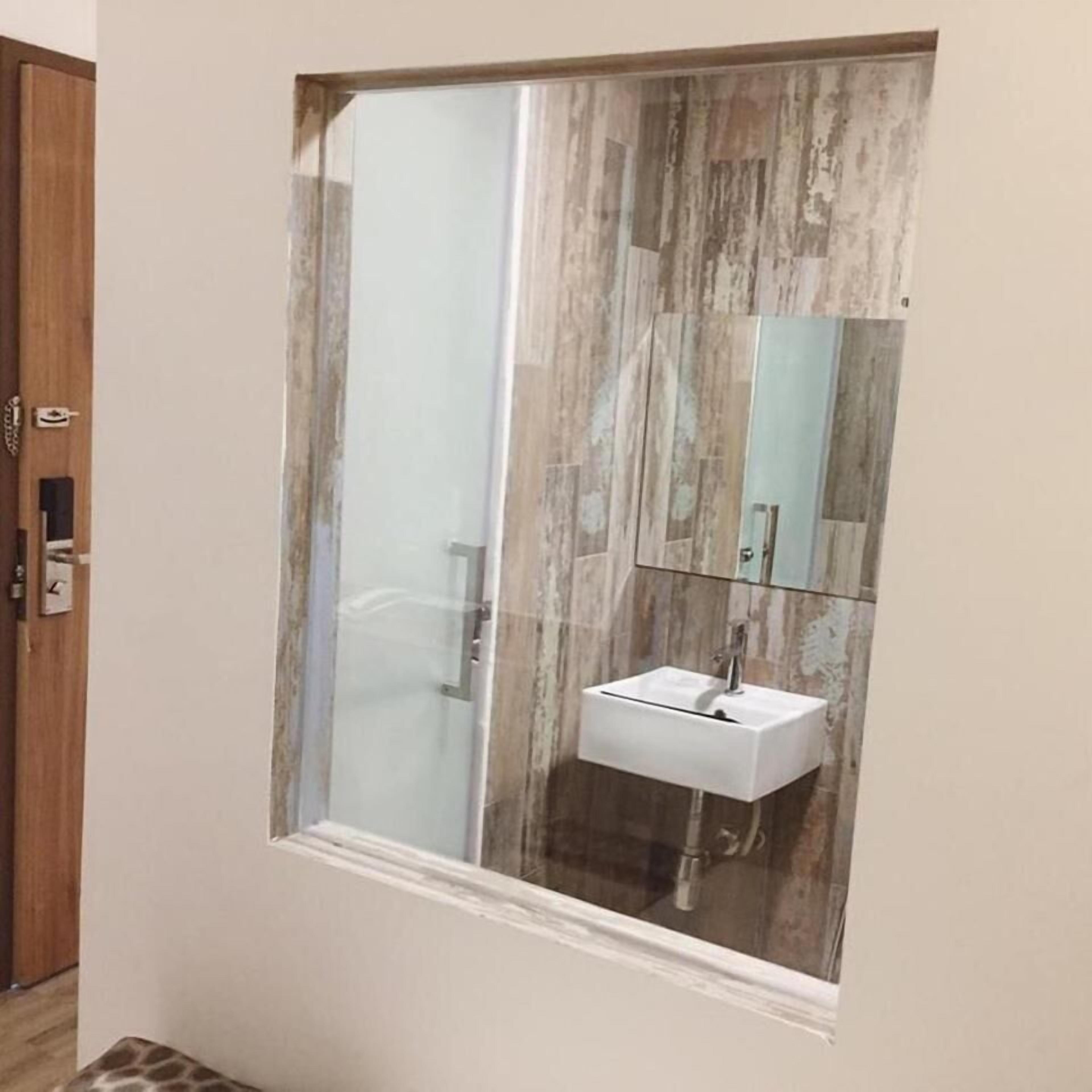 Un baño con cabina de ducha de vidrio, un lavabo blanco y un espejo sobre él.