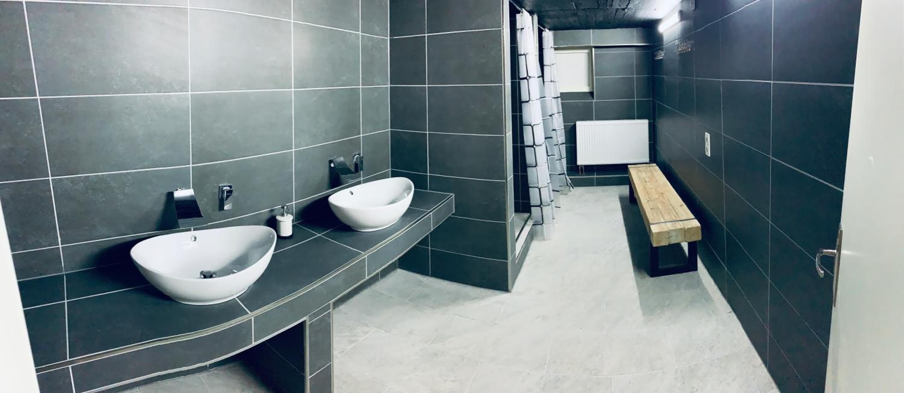 Ein modernes Badezimmer mit zwei Waschbecken, einer Ablage und einer Toilette.