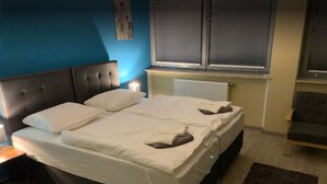 En dobbeltseng med hvide sengetøj, en mørk sengegavl og et natbord med lampe.