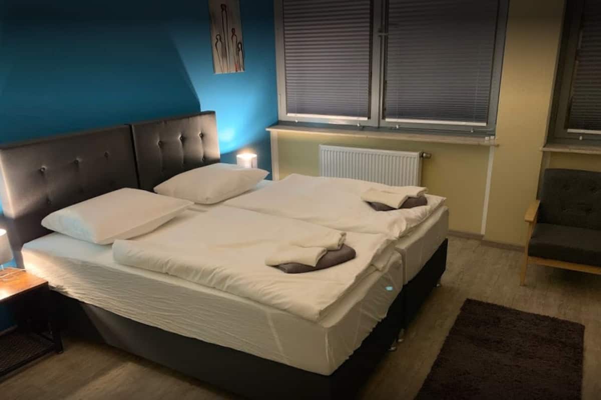 A double bed with white linens, a dark headboard, and a bedside table with a lamp.
