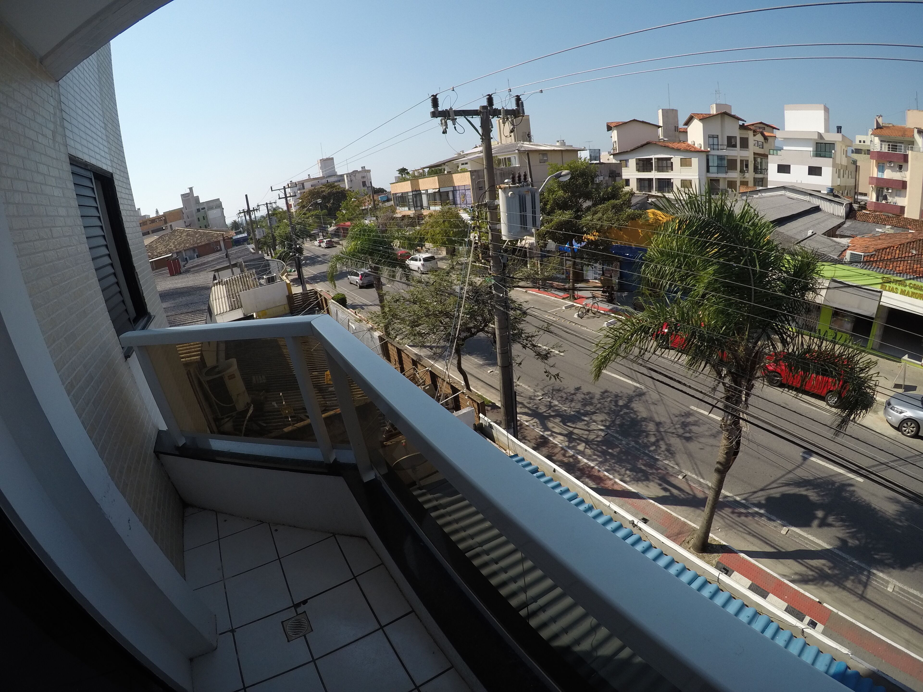A balcony with a view of a street, buildings, and a clear sky.