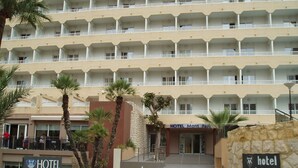 A multi-story hotel with a central entrance, palm trees, and a stone wall with a sign. - Mont-Park Hotel (Benidorm)