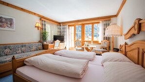 A bedroom with a large bed, a sofa, a desk, and a chair. - B&B Garni Casa La Val (Tujetsch)