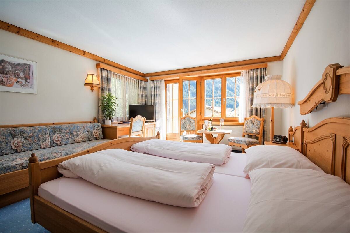 A bedroom with a large bed, a sofa, a desk, and a chair.