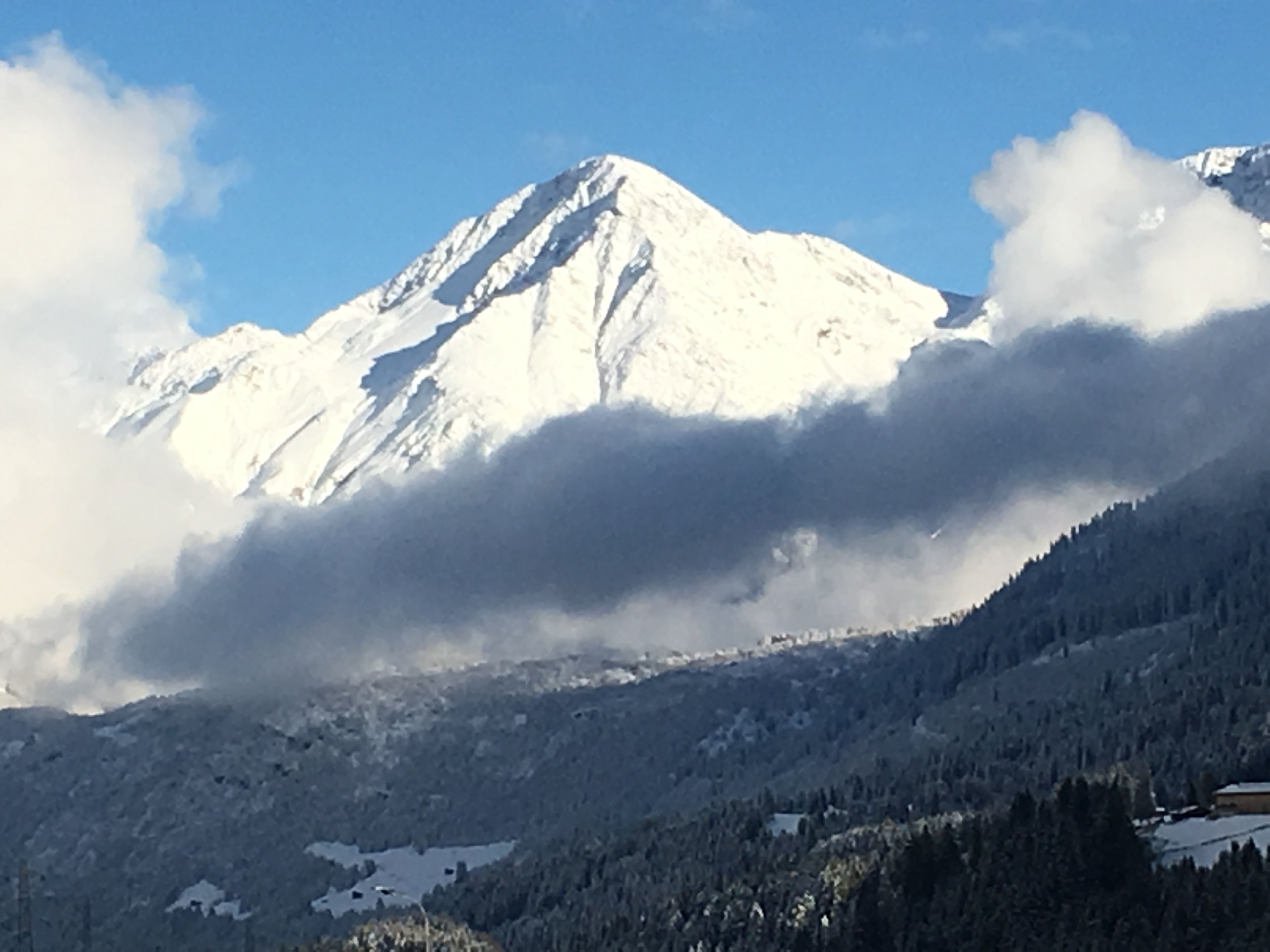 Una montaña nevada con cielo despejado y nubes.