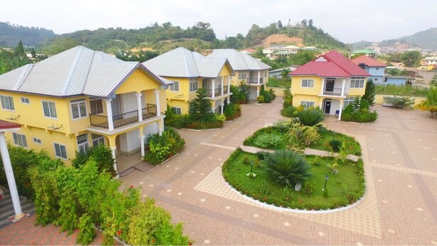Zona residencial con varias casas de dos pisos, un patio central con jardín circular y un paisaje montañoso al fondo.