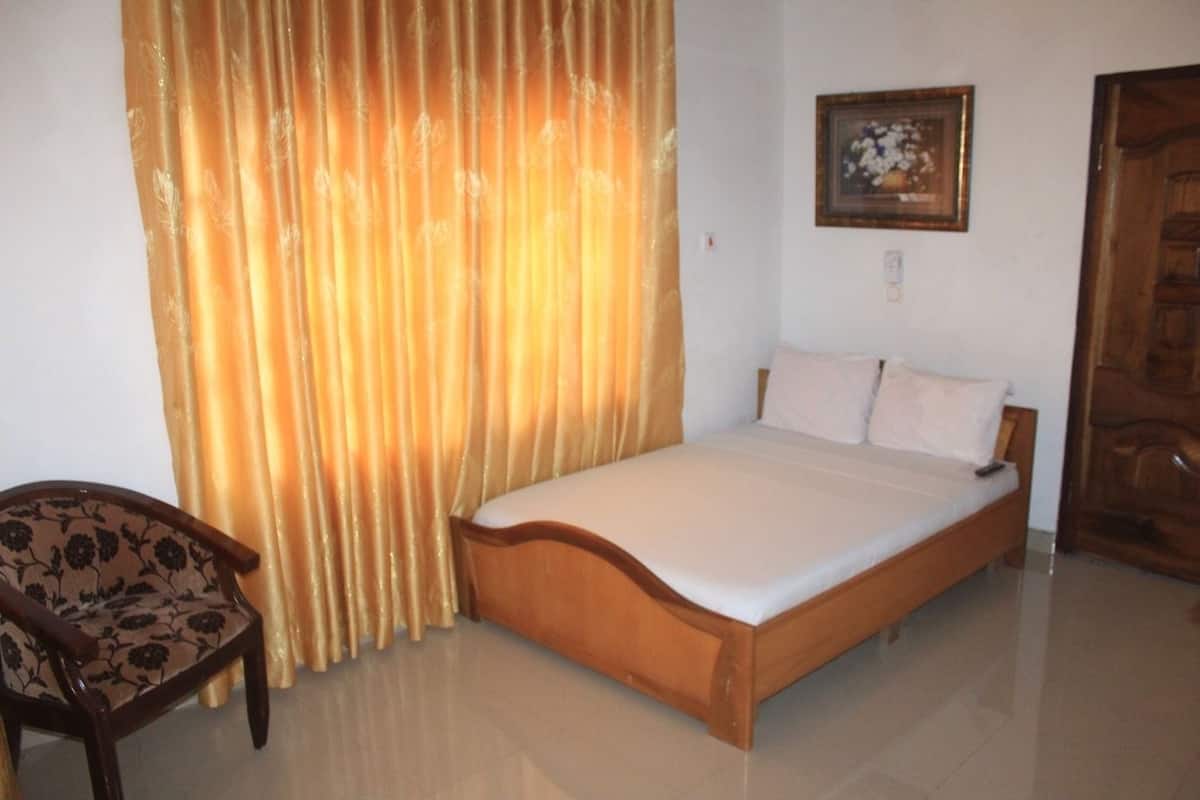 A bedroom with a wooden bed, a chair, and a curtain.