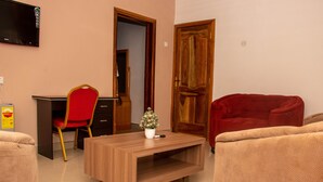 Una sala de estar con una mesa de centro de madera, una silla roja, un sofá rojo y un televisor montado en la pared.