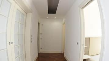 A hallway with wooden flooring, white walls, and a ceiling light fixture.
